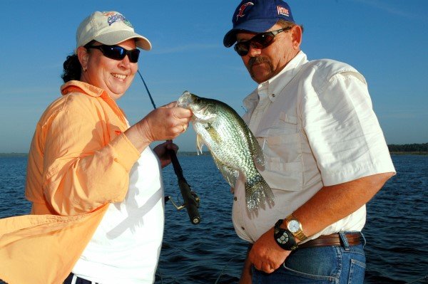 Baker looks on and admires a crappie caught by Kim Newton while fishing Orange Lake near Ocala, Florida.